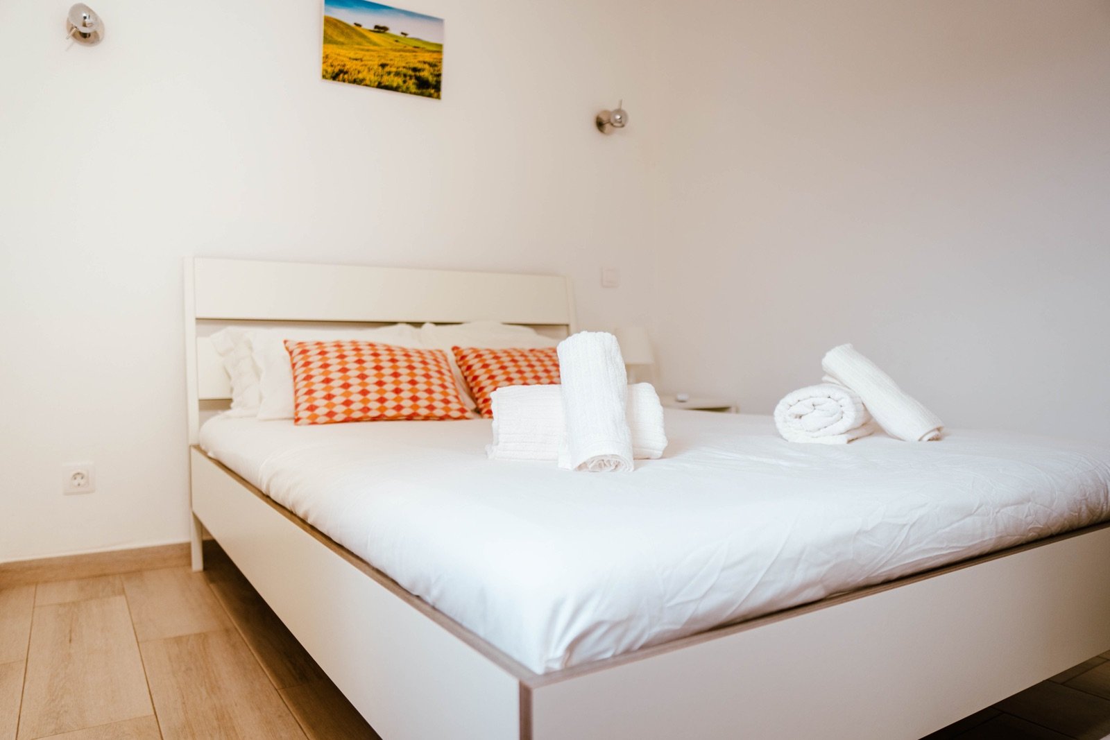 Quarto de casal da Casa Faro com almofadas em tons de laranja